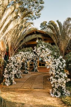 Beautiful floral archway at an outdoor wedding venue under a clear sky.