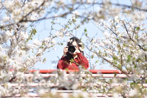 A Woman in Red Long Sleeves Using Her Camera