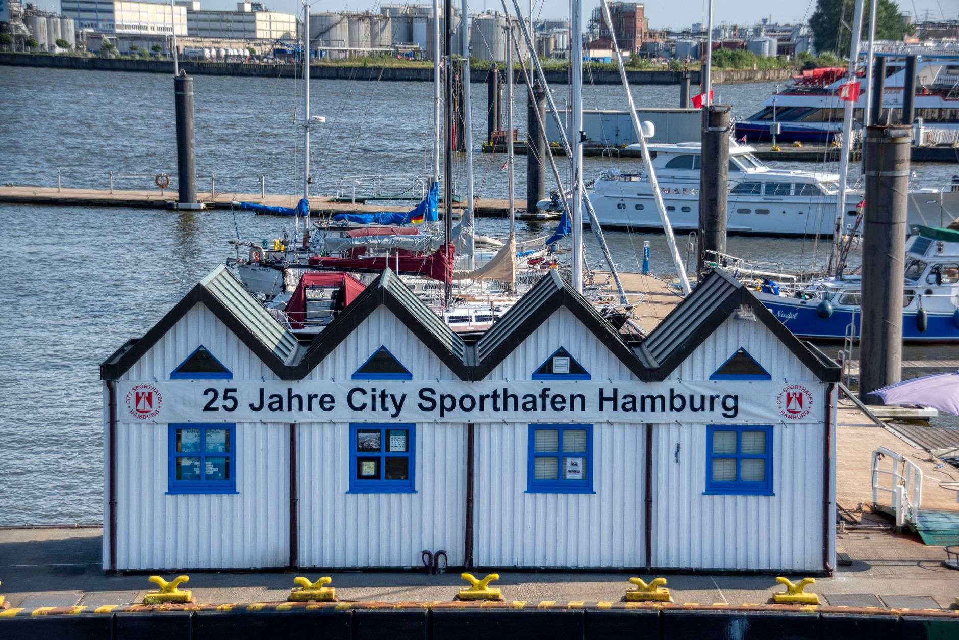 Vibrant scene at Hamburg's city sport harbor with boats and a prominent white building.