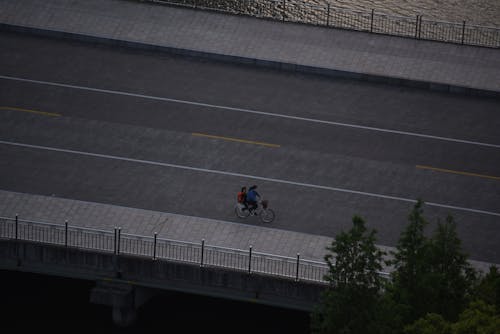 Two People Riding Bicycle Across The Bridge