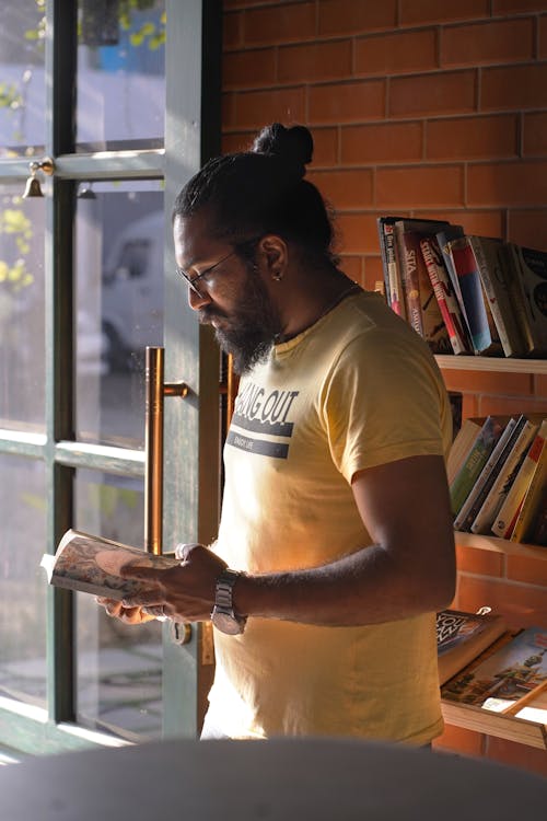 Bearded Man in Yellow Shirt Reading a Book by the Doorway