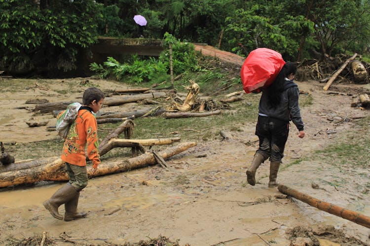 A Woman And A Boy Walking On A Muddy Pathway