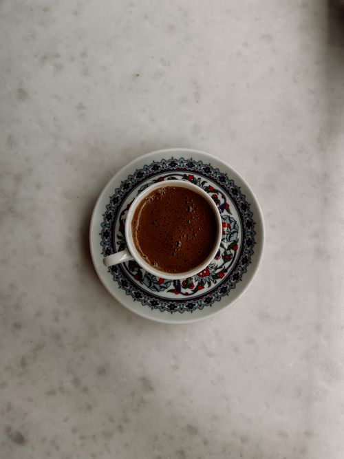 Free Overhead view of a steaming espresso in a decorative cup and saucer on a marble table, offering a touch of elegance. Stock Photo
