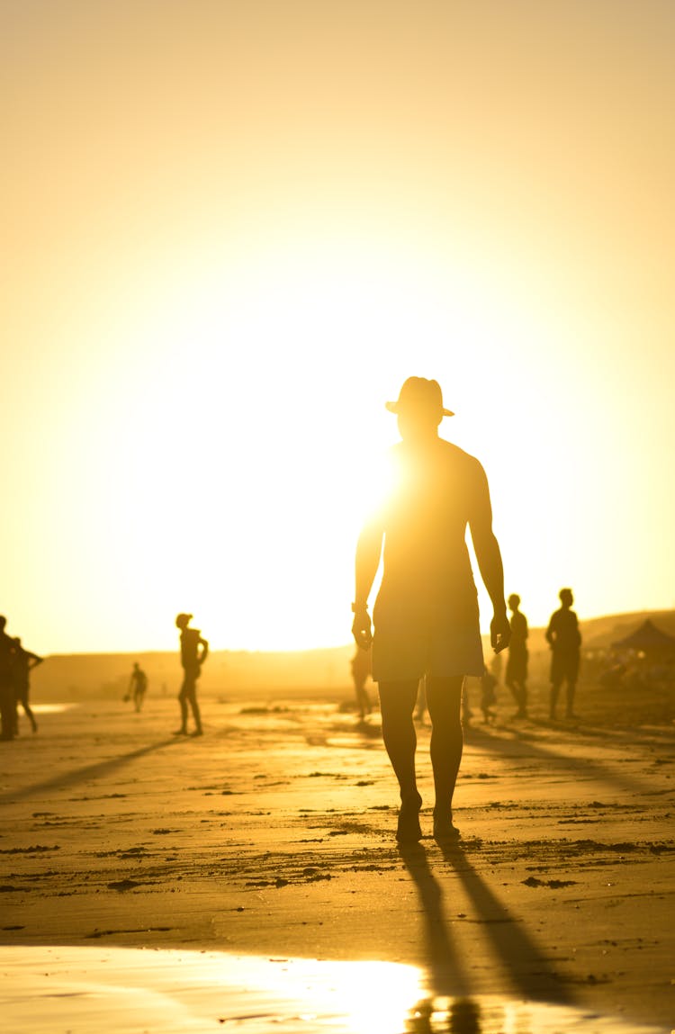 Silhouette Of A Man In A Hat Walking On The Beach 