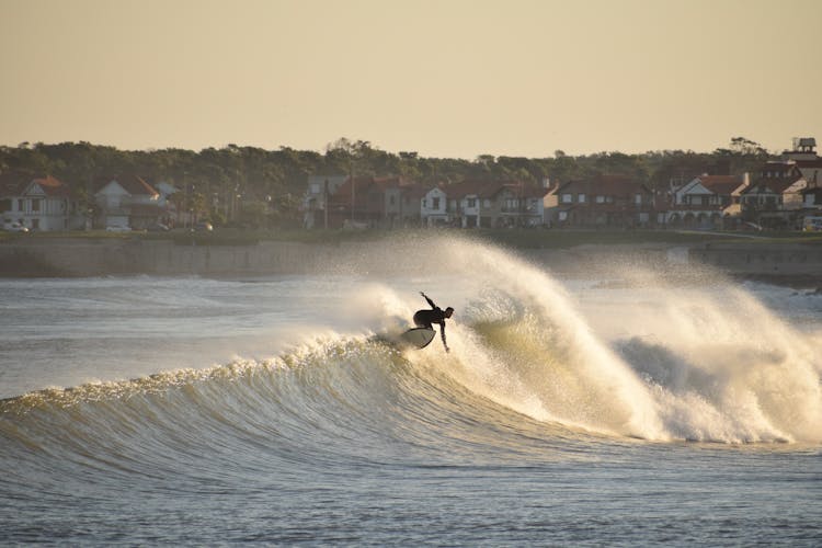 Man Surfing On Small Wave By Shore