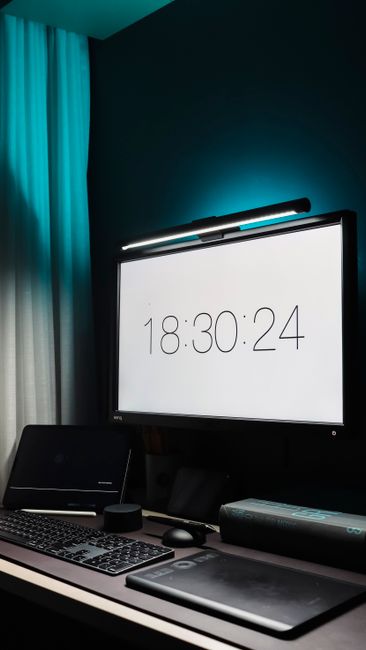 Contemporary desk setup featuring a digital clock on a monitor in a sleek office environment.