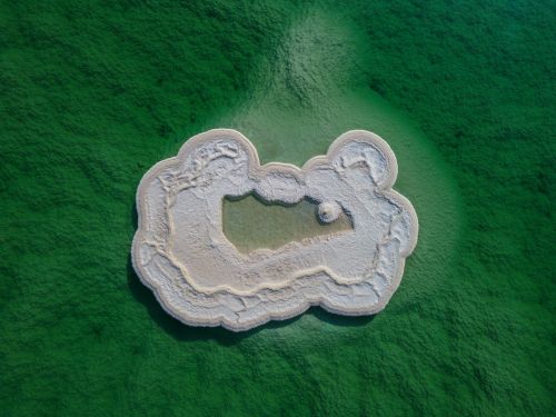 Free Stunning aerial shot of a white salt island in a vivid green water setting. Stock Photo
