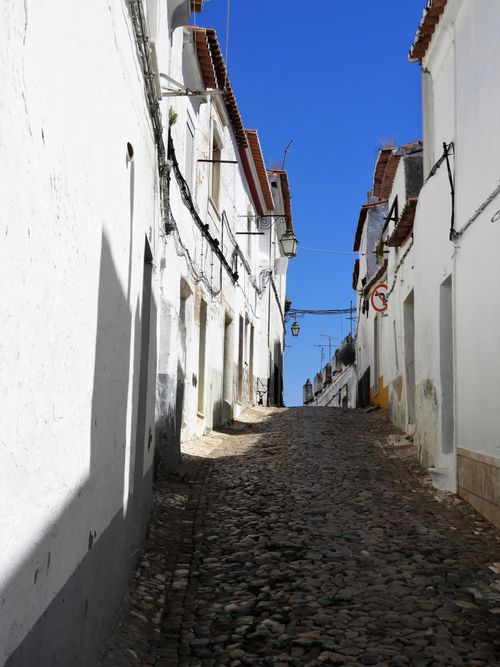 Free Explore the rustic beauty of a cobblestone street in Monsaraz, Portugal under a clear blue sky. Stock Photo