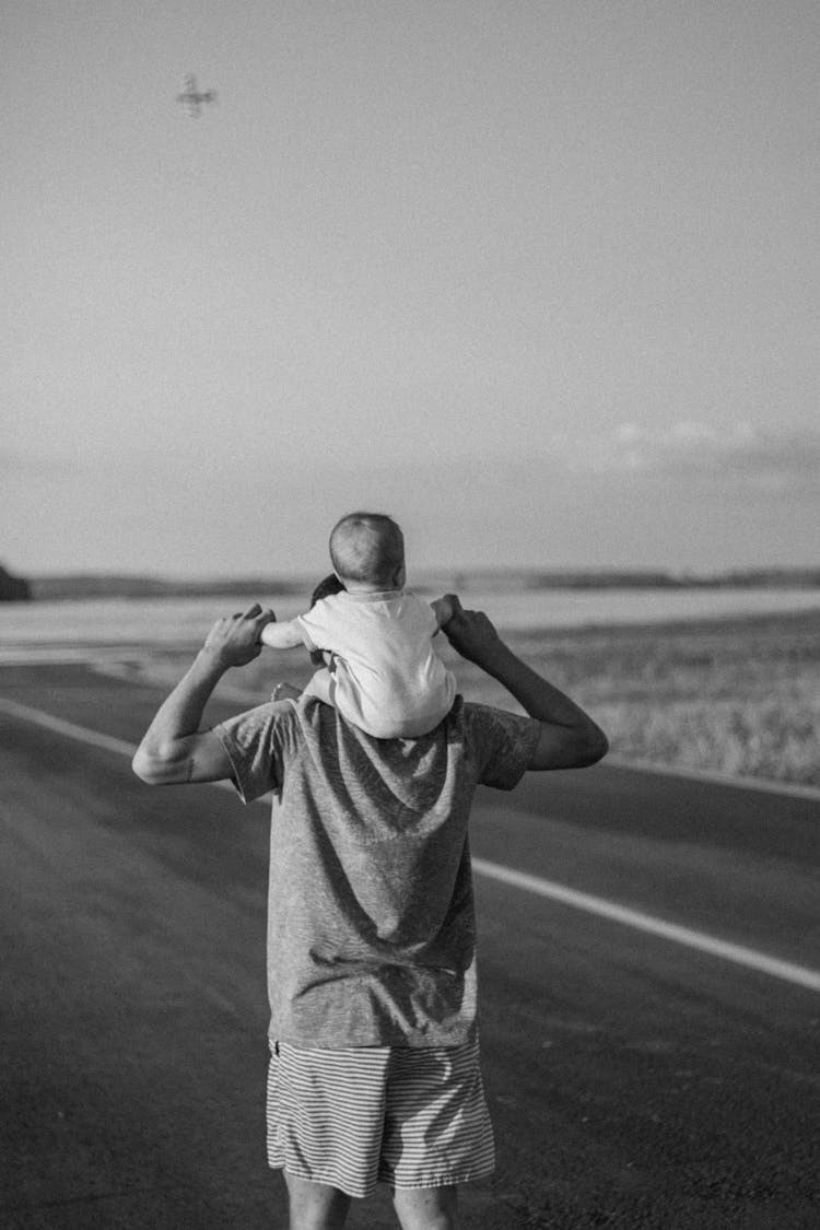 A Man Carrying A Baby On His Shoulder 