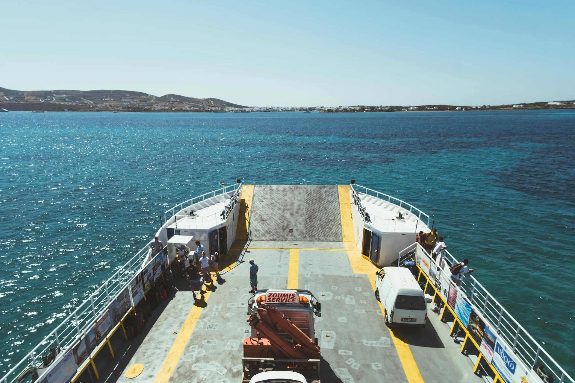 View from a ferry deck with passengers enjoying the ocean view and distant coastline.