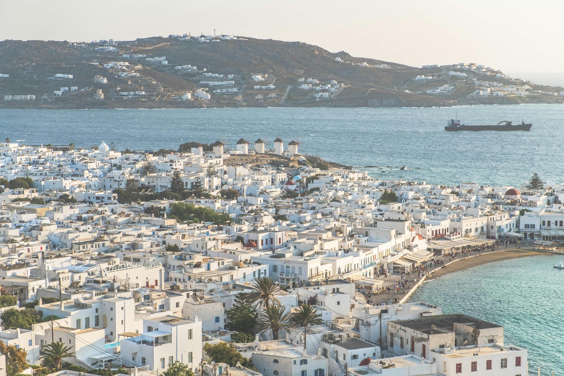 Aerial view of Mykonos Old Port in Greece showcasing traditional white buildings and the Aegean Sea.