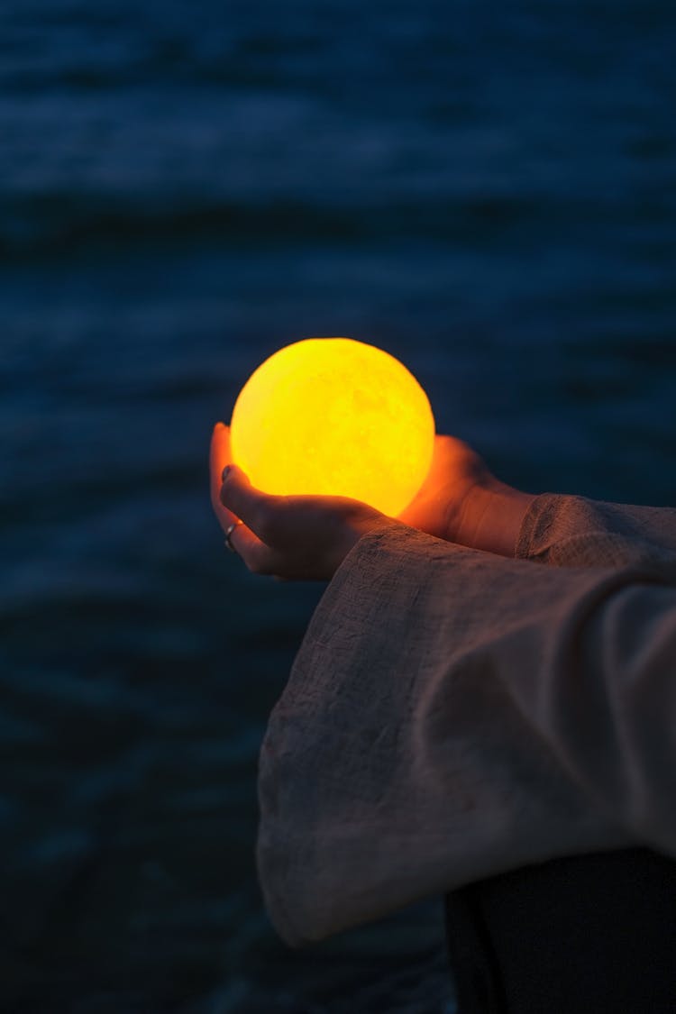 Hands Holding Illuminated Ball At Night