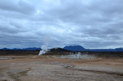 Free A dramatic Icelandic landscape showcasing steam vents and mountains under cloudy skies. Stock Photo