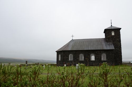 Free Stone church in Iceland with a lush grass field and a white, cloudy sky. Stock Photo