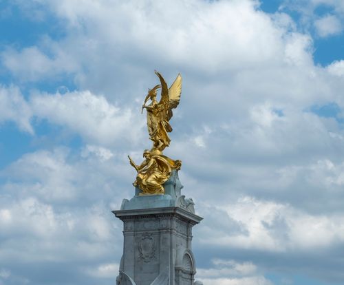 Free Majestic golden statue atop a monument against a bright blue sky near Buckingham Palace in London. Stock Photo