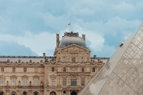 Facade of the Louvre Museum in Paris Under White Clouds