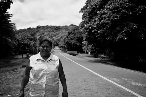 Grayscale Photo of a Woman Standing on the Road 