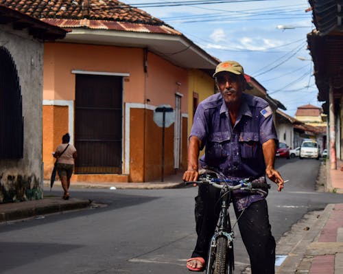 Man in Blue Polo Riding Bicycle on Street