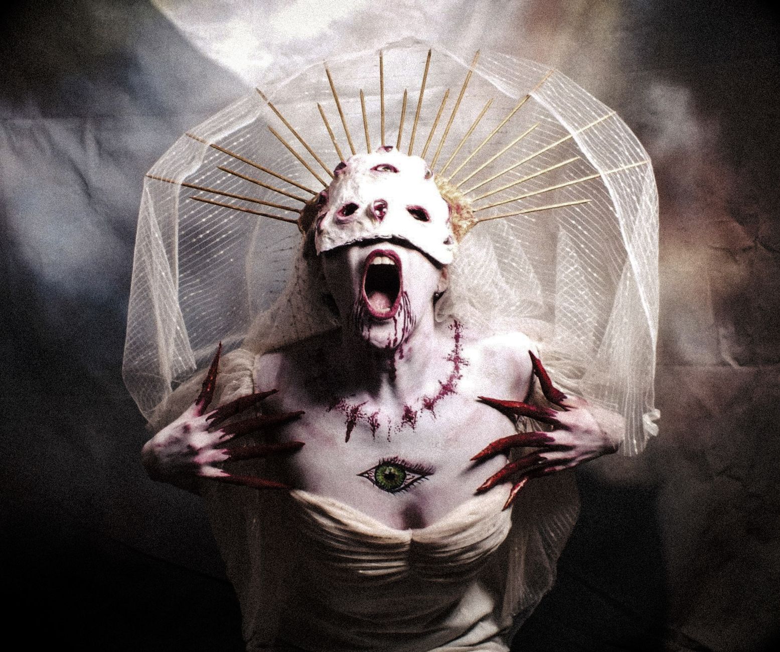 Gothic woman with a haunting costume, veil, and painted mask in an artistic horror portrait.