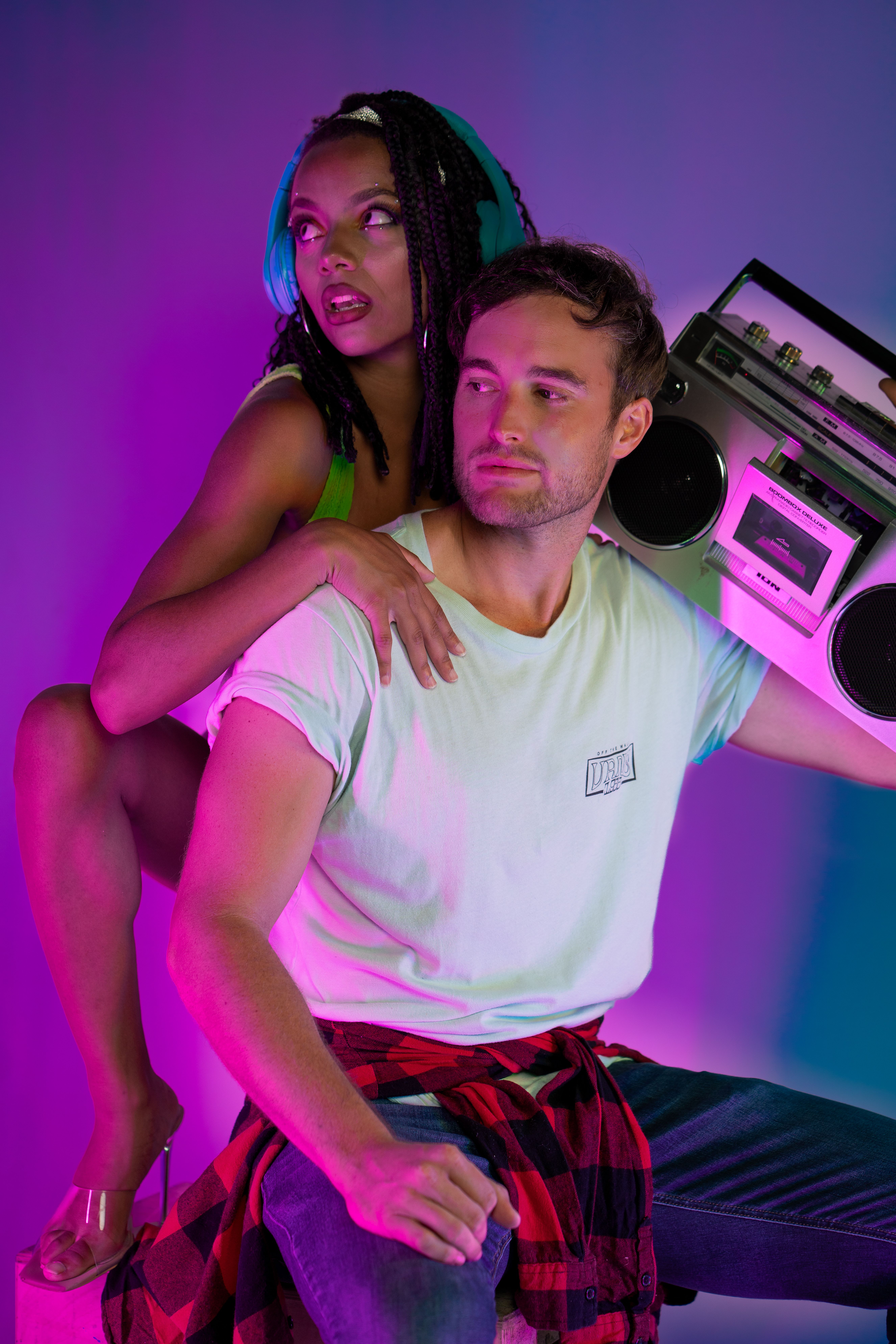 Dynamic portrait of two individuals with a retro boombox under neon lights, showcasing vivid expressions.