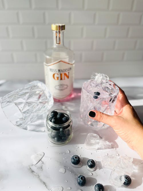 Hand Holding Glass with Cold Gin and Ice Cubes