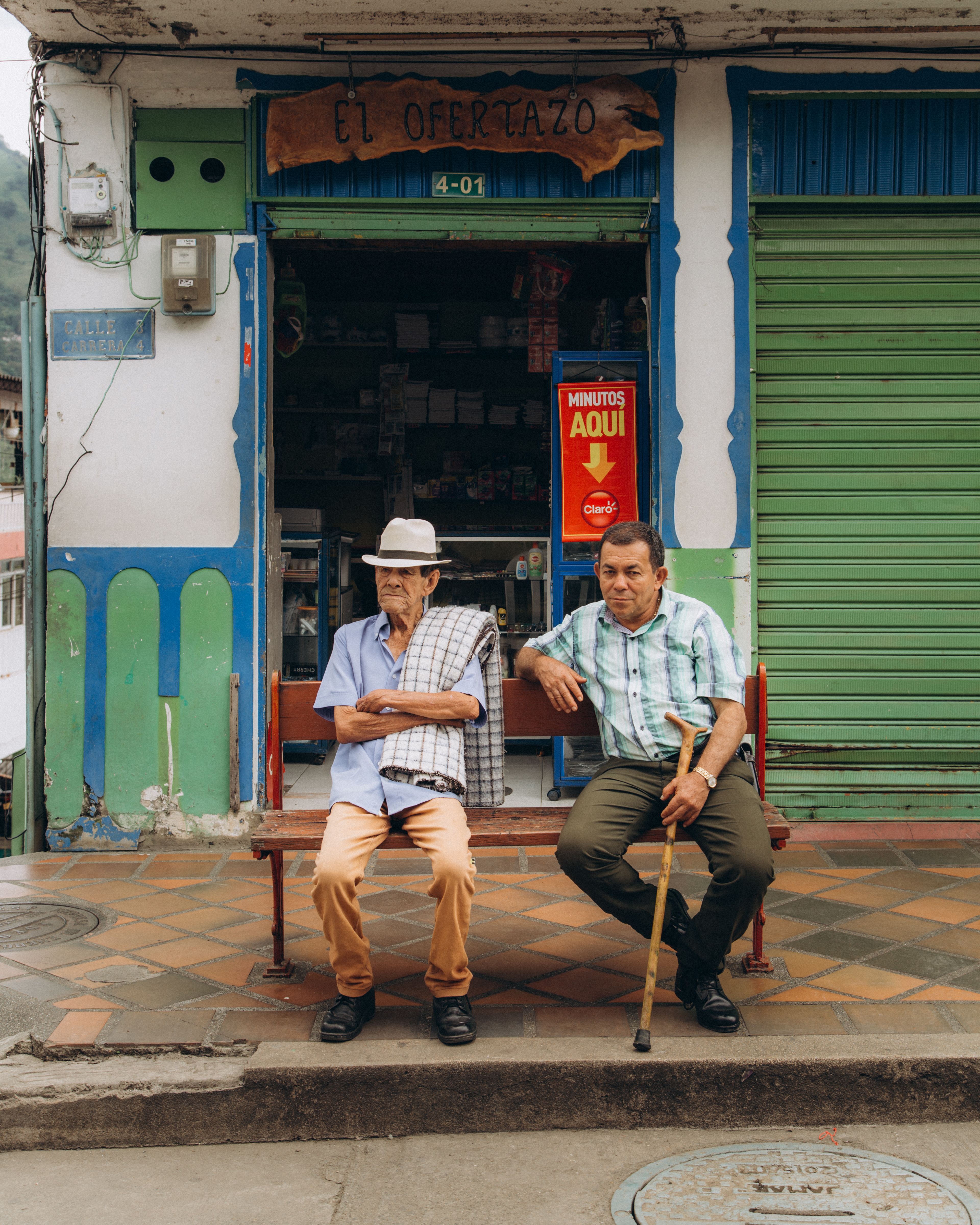 two men sitting on a bench on a street