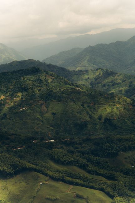 Breathtaking aerial view of lush green mountains and valleys with cloudy skies.