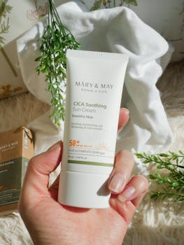A soothing CICA sun cream held outdoors with green foliage backdrop.