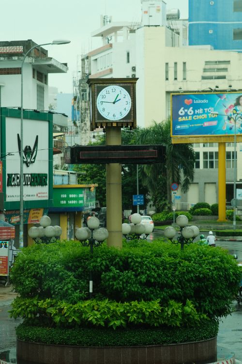 Free City roundabout with large clock tower and colorful advertising billboards in urban setting. Stock Photo