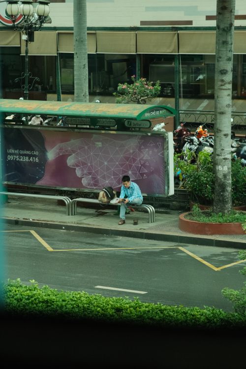 Free A man in Vietnam sitting at a bus stop, waiting for public transport. Stock Photo