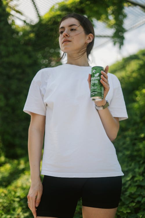 Woman in White Crew Neck T-shirt Holding Green Can