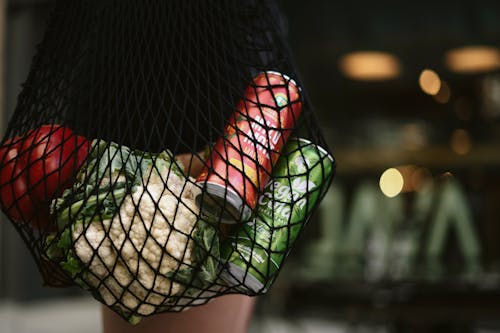 Drinks in Can and Fresh Vegetables in a Mesh Bag