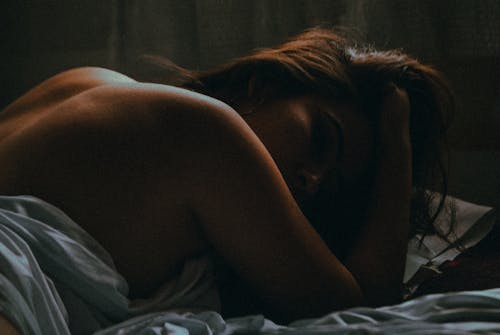 Shirtless Woman Lying on a Bed