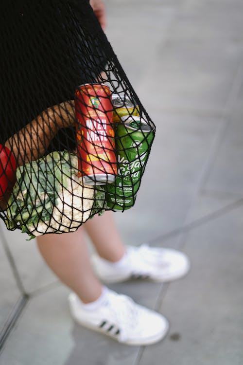 Person Holding a Net Bag with Groceries