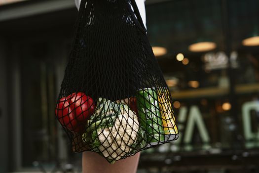 Close-up of vegetables and a can in a net bag, emphasizing eco-friendly shopping.
