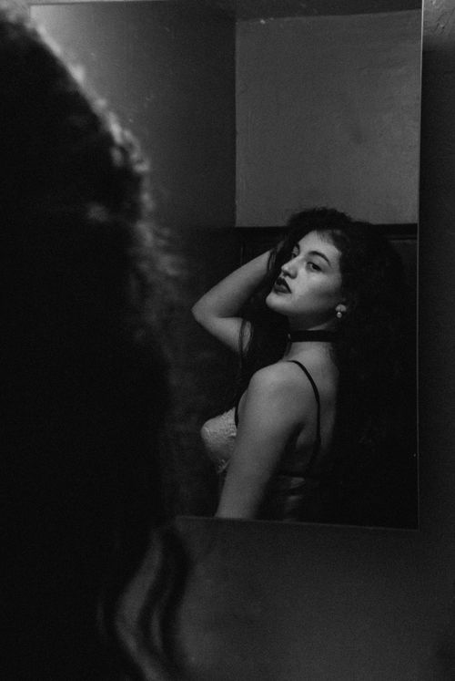 Free Elegant monochrome portrait of a woman posing in front of a mirror with a thoughtful expression. Stock Photo