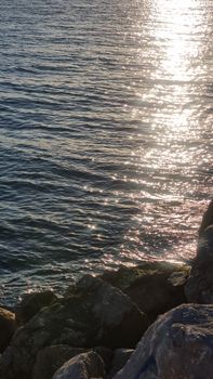 Sunrise over rocky coastline in Istanbul, Turkey, with shimmering sea reflections.