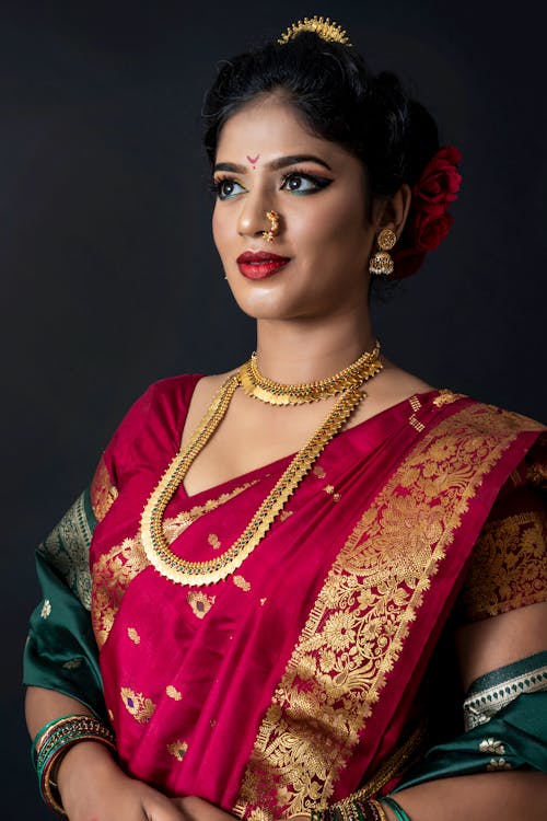 Woman in Gold and Red Sari Wearing Gold Jewelries