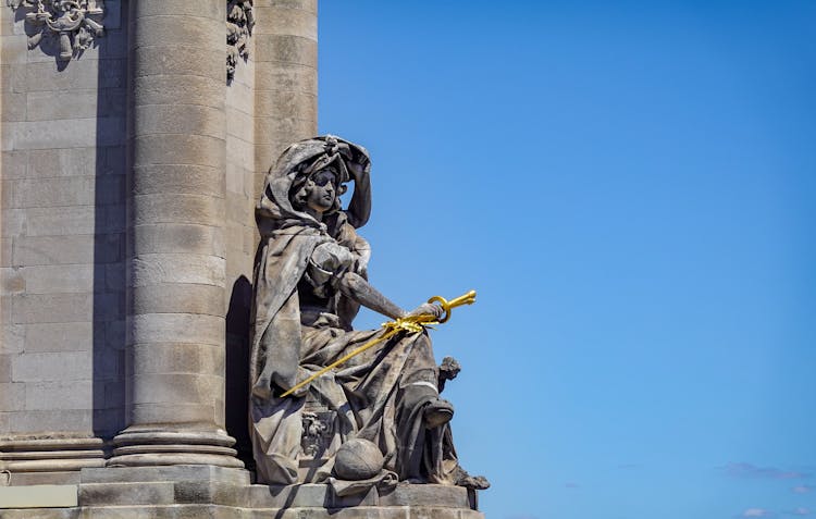 A Sculpture Of A Woman Holding A Golden Sword