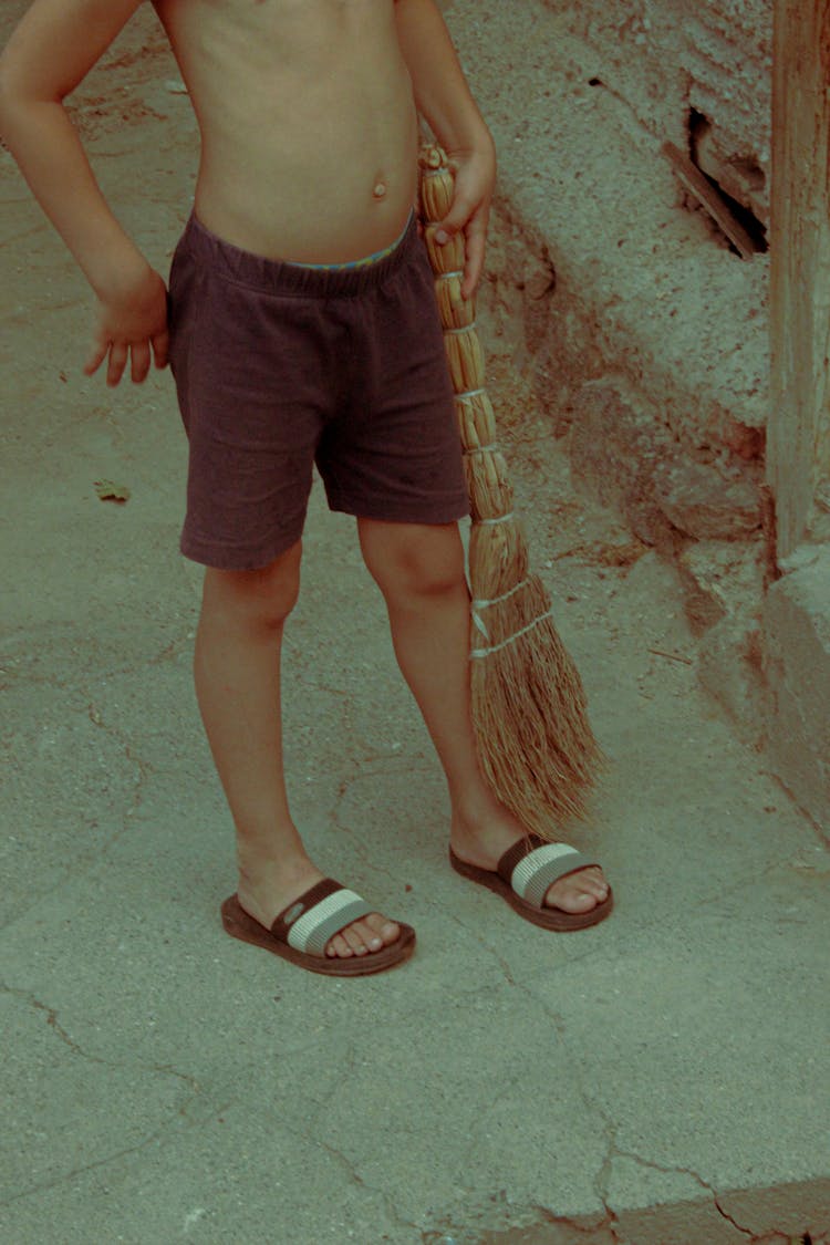 A Shirtless Boy Holding A Broom