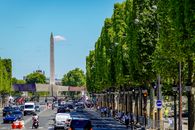 Busy Paris street with the iconic Luxor Obelisk at Place de la Concorde on a sunny day.