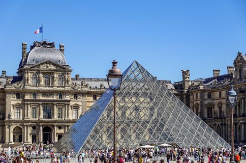 Free Iconic Louvre Pyramid with bustling crowds in Paris, France on a sunny day. Stock Photo