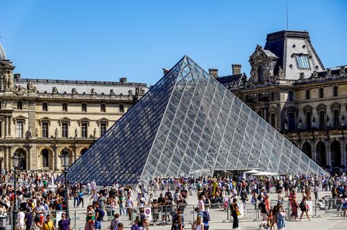 Free Crowded scene of the Louvre Pyramid in Paris, a famous historical landmark and tourist attraction. Stock Photo