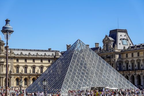 Free A bustling view of the Louvre Pyramid surrounded by architecture in Paris. Stock Photo