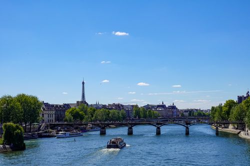 Free Charming view of the Eiffel Tower with boats on the Seine River and historic architecture in Paris. Stock Photo