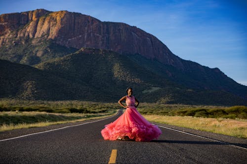 Free Woman in Pink Dress Standing on Asphalt Road Stock Photo