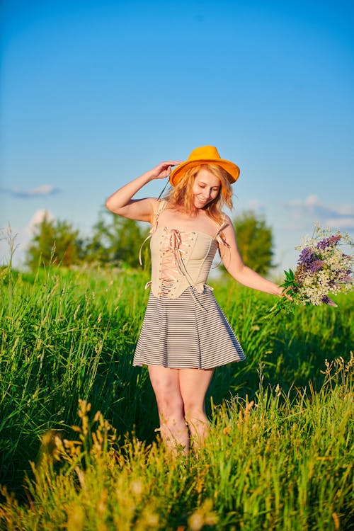 Beautiful Woman Holding Flowers Standing in a Field