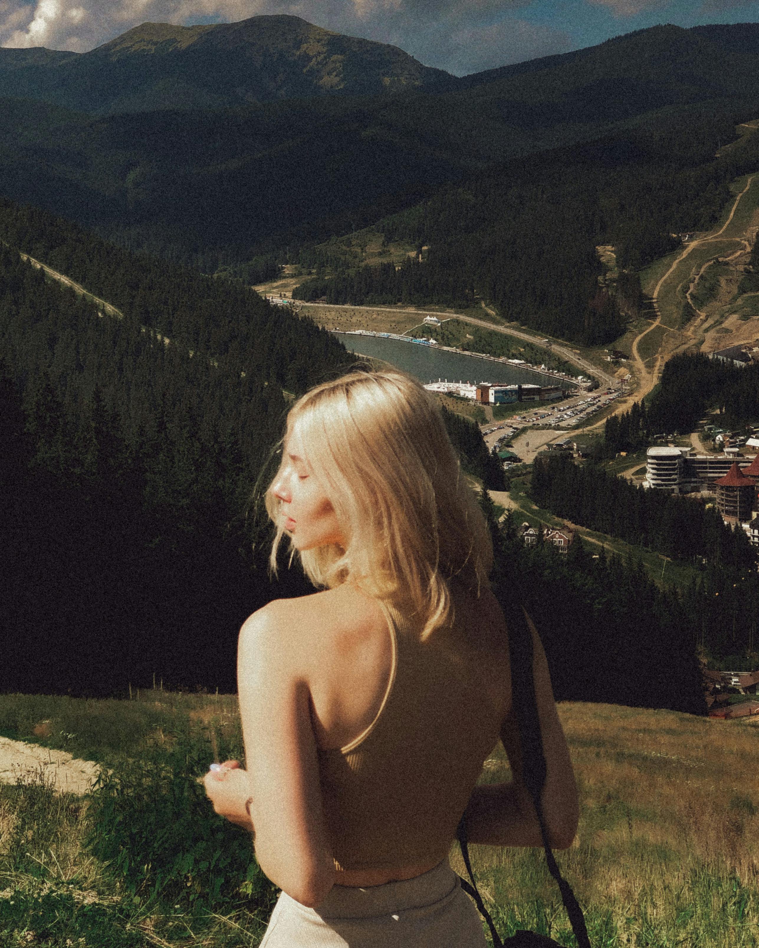 Young woman with blonde hair enjoying a breathtaking mountain view in summer.