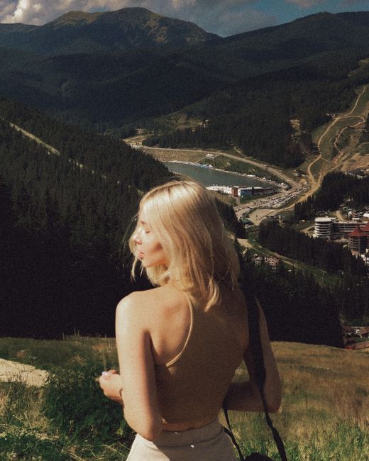 Young woman with blonde hair enjoying a breathtaking mountain view in summer.