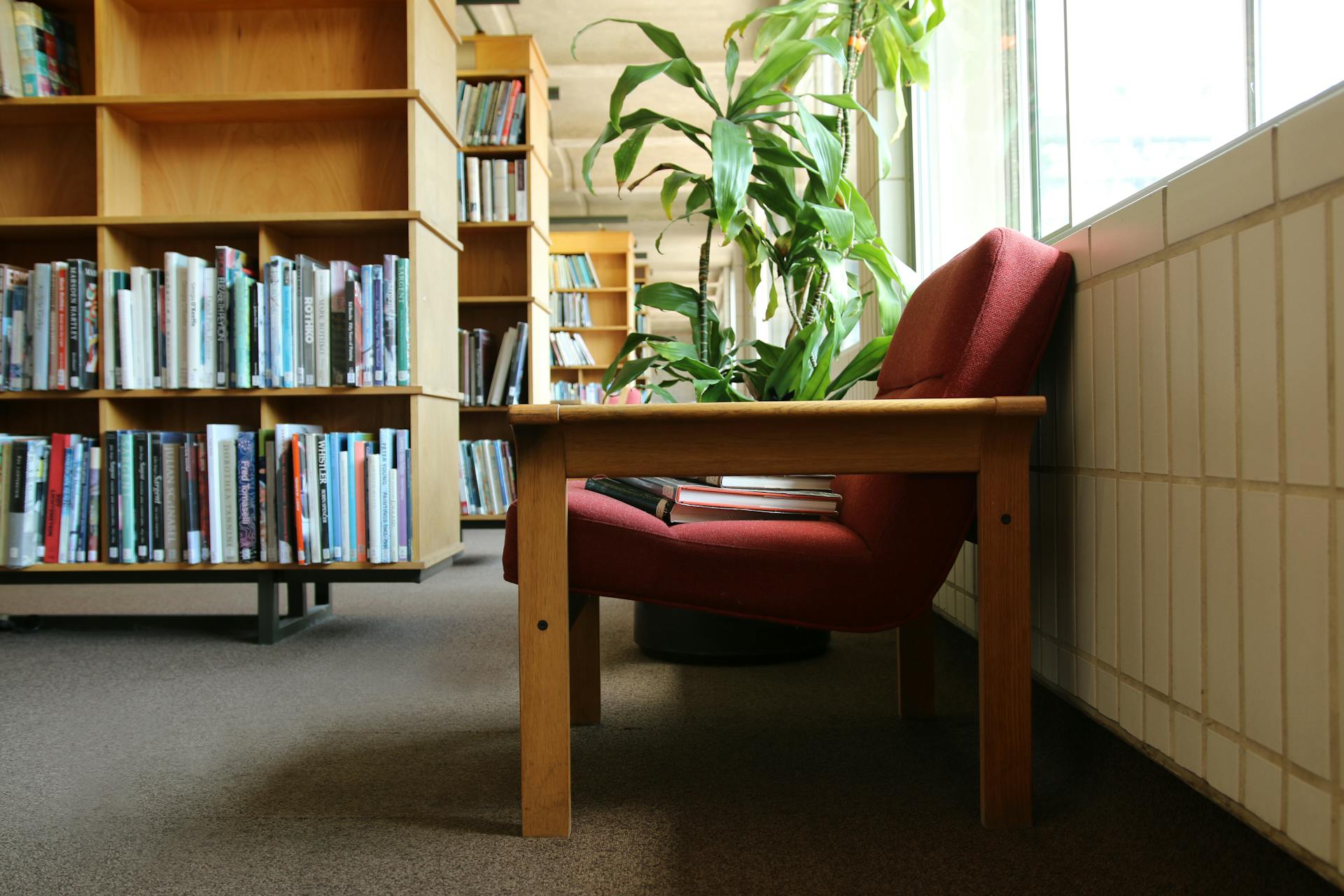 A cozy reading corner with an armchair and shelves of books in a UK library.